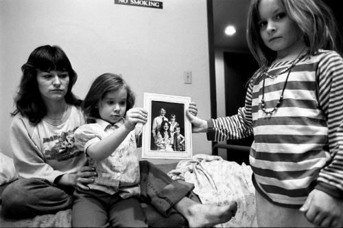 Mary and her daughters holding a family portrait with their father, Minneapolis