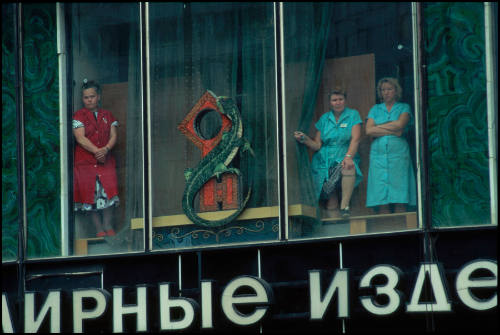 Three department store workers watch a mass funeral from the store window following the failed coup attempt, Moscow, Russia