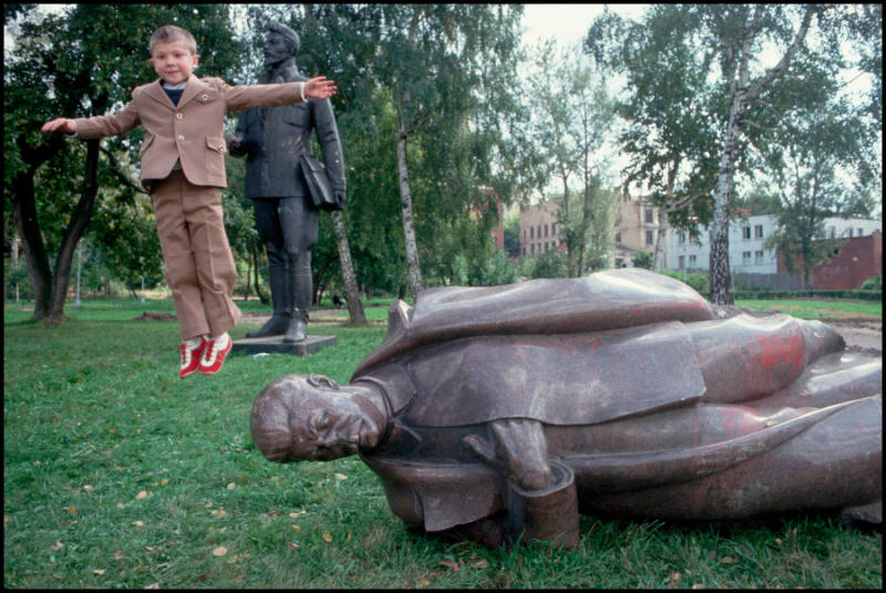 A young Russian boy jumps off the head of a toppled Stalin statue, placed in a "cemetery" following the failed coup attempt, Moscow, Russia