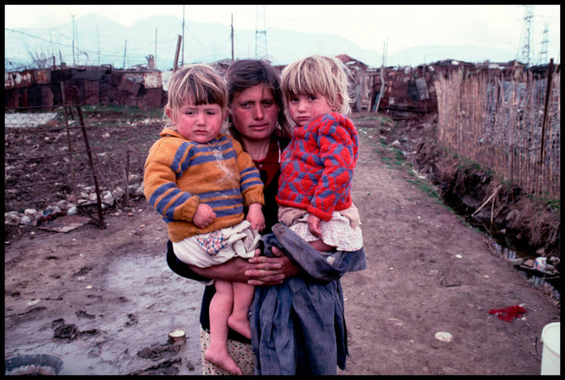 A mother and her daughters on a muddy path leading to a shanty town in Albania's capital city, Tirane