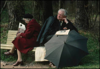 A middle-aged man and woman turn their backs on each other while sitting on a park bench in Serebryaniy Bor, Moscow, Russia