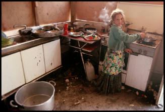 A girl stirs a pan on a stove, Sardinia, Italy