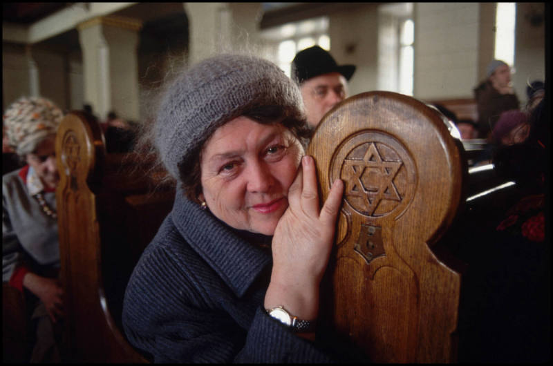 A woman sitting in the pews of a synagogue, touching the Star of David, Moscow